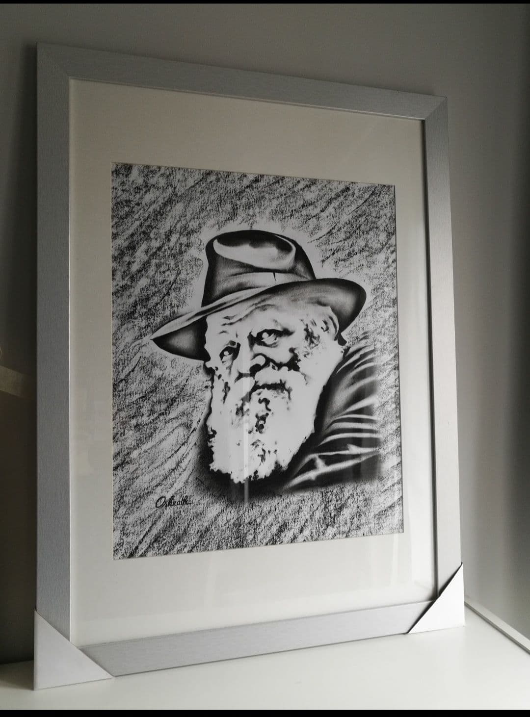 Le portrait du Rabbi au fusain dans un cadre argenté, posé contre un mur