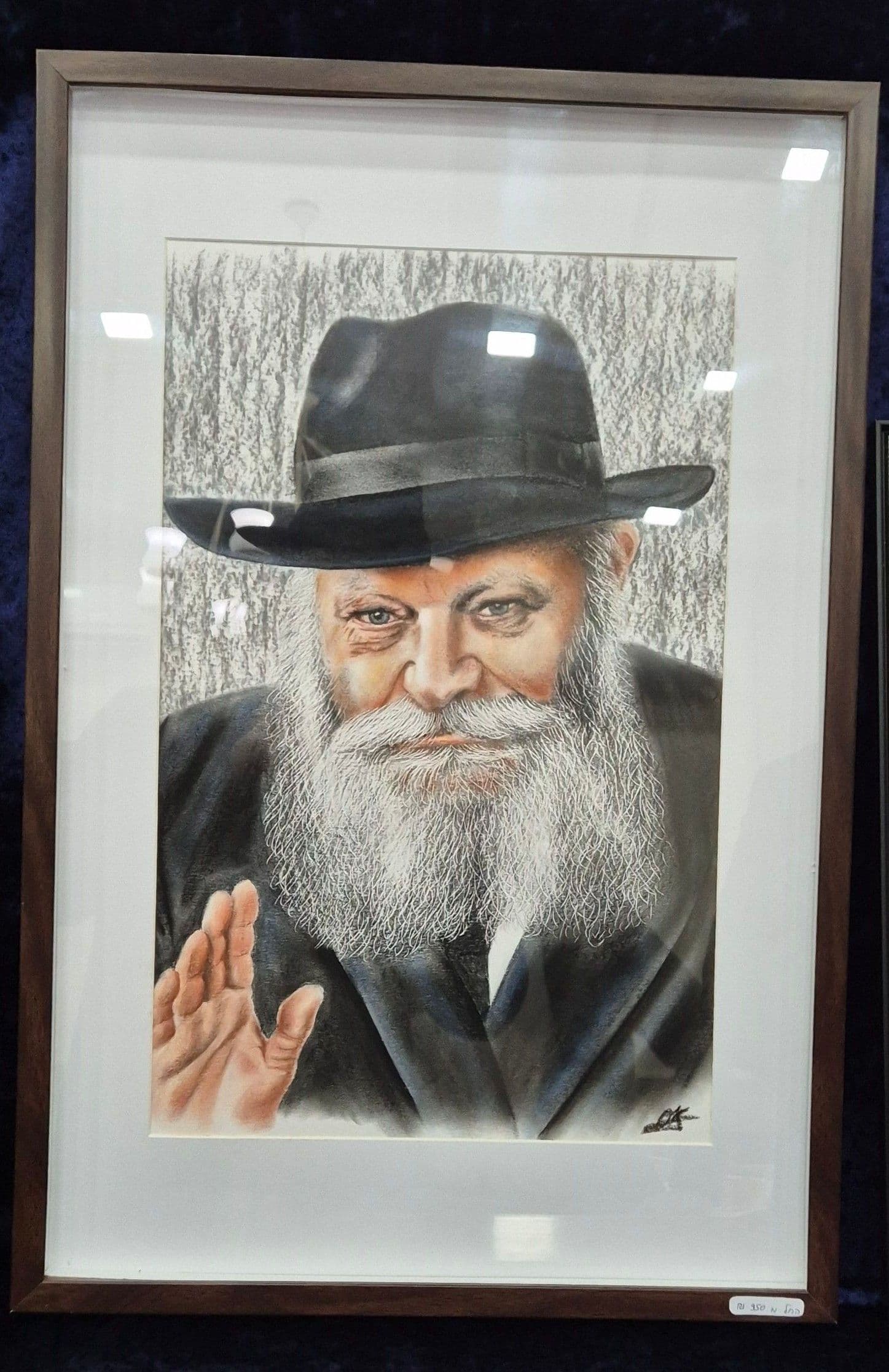 Le portrait en couleur du Rabbi dans un cadre en bois foncé avec passe-partout blanc, sur un velours bleu nuit