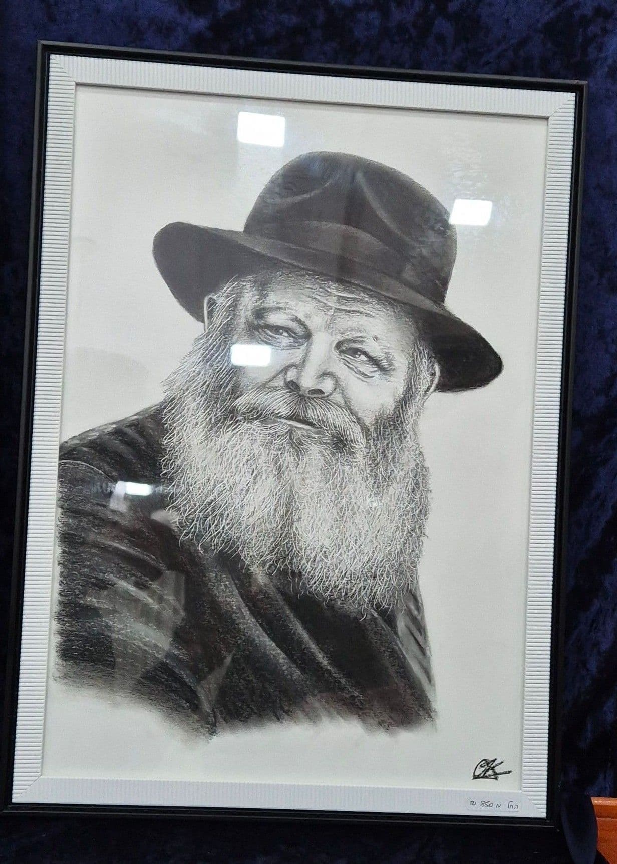 Le portrait du Rabbi de trois quarts dans un cadre noir, posé sur un velours bleu nuit