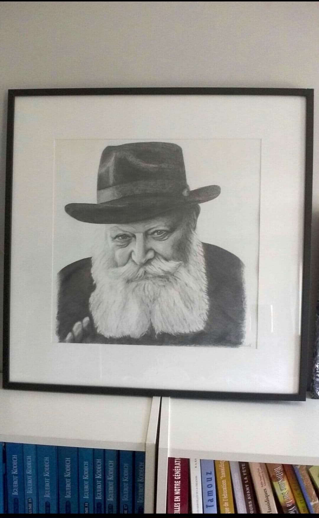 Portrait du Rabbi au crayon encadré, posé sur une bibliothèque
