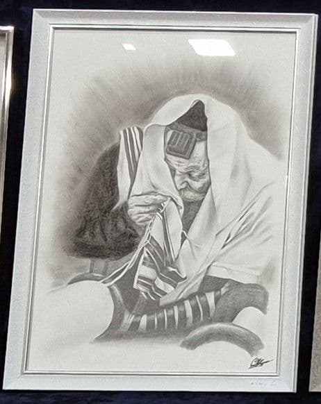 Le dessin du Rabbi en prière dans un cadre blanc, posé sur un velours bleu nuit